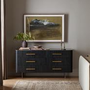 Modern black dresser with gold handles, sleek design, features spacious drawers, decorative plant and candles on top.