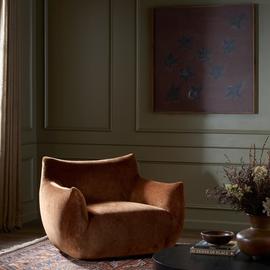 Modern brown velvet armchair in an elegant room with muted decor, showcasing luxury and comfort.