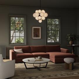 Modern living room with a rust-colored sectional sofa, marble coffee table, and stylish pendant light in a cozy setting.