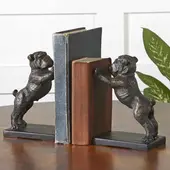 Decorative bulldog bookends with a metallic finish holding books upright on a wooden tabletop.