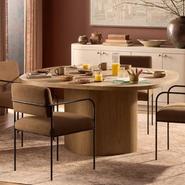 Modern dining room with elegant oak table and chairs, set with breakfast items in a warm, earthy-toned setting.