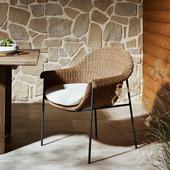 Rattan dining chair with white cushion in a cozy patio setting, ideal for outdoor relaxation and comfort.