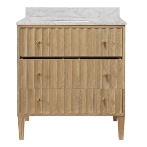 BATH VANITY WITH VERTICAL FLUTED DETAIL ON DRAWERS IN CERUSED OAK WITH WHITE MARBLE TOP, PORCELAIN SINK, AND POLISHED BRASS KNOBS